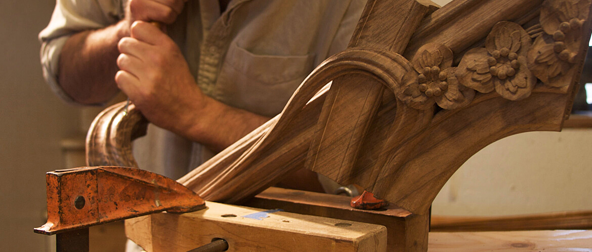 A woodcarver for Agrell Architectural Carving works on a component for an Art Nouveau-style bed.