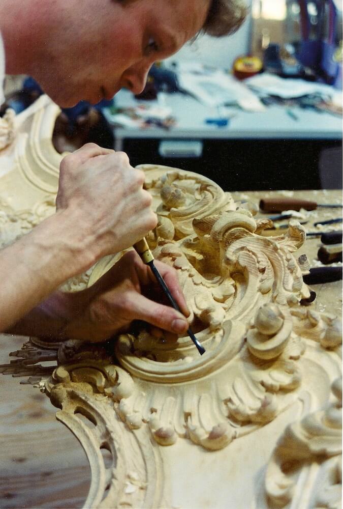 A woodcarver for Agrell Architectural Carving works on an English Rococo fireplace